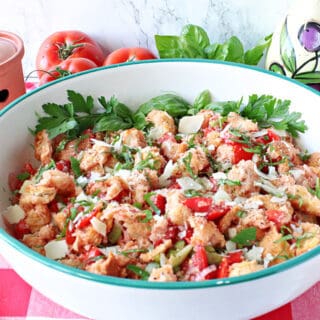 A large serving bowl filled with Italian Panzanella Salad topped with fresh basil and cheese.