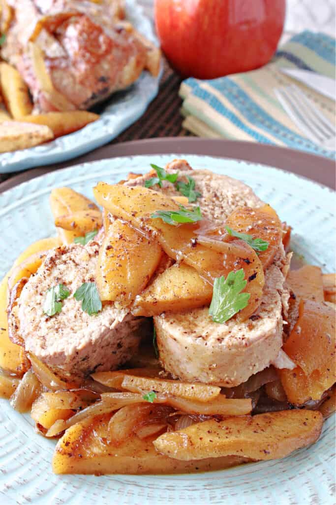 A light blue plate with a serving of skillet pork tenderloin with cinnamon apples and onions.