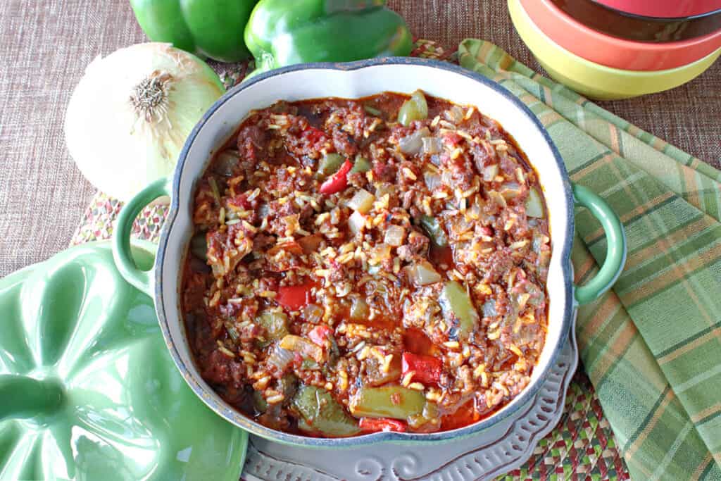 An overhead photo of a cute green pepper shaped casserole dish filled with Stuffed Green Pepper Stew along with some green napkins on the side.