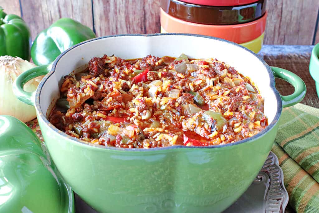 A green pepper shaped pot of Stuffed Green Pepper Stew along with some fresh green peppers in the background for Soup, Stew, and Chowder Recipe Roundup.