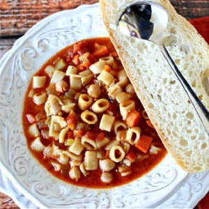 A bowl of Tuscan Pasta Soup with a slice of bread and a spoon.