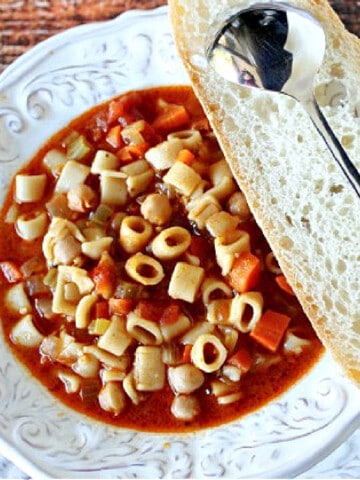 A bowl of Tuscan Pasta Soup with a slice of bread and a spoon.