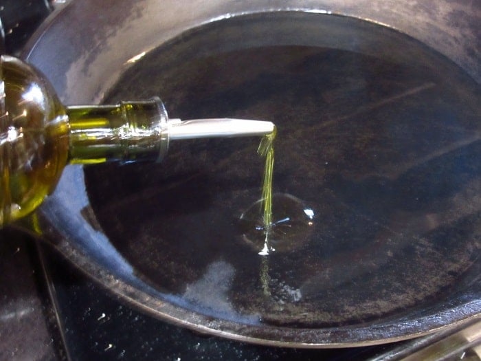 Oil being added to a cast iron skillet.