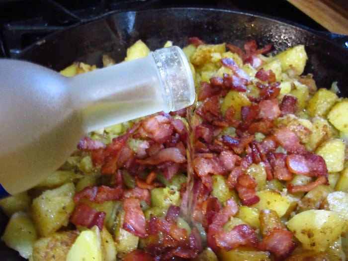 Vinegar being added to potatoes in a skillet to make German Fried Potatoes.