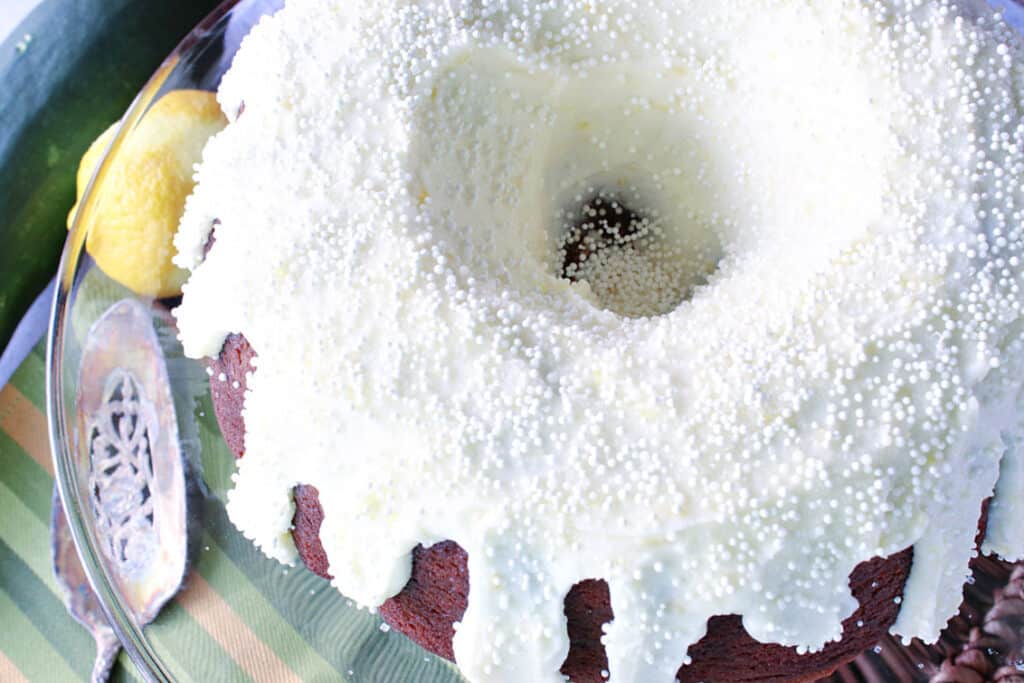 An overhead closeup photo of a Gingerbread Bundt Cake with Zucchini covered with Lemon Ginger Buttercream Frosting and white non-pareils.