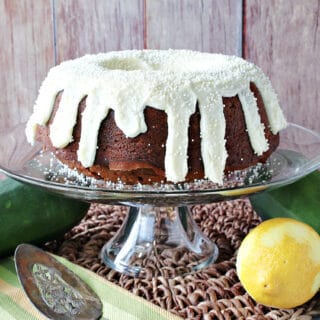 A Gingerbread Bundt Cake wit Zucchini on a cake stand with a lemon and zucchini on the table.