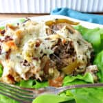 A serving of Savory Italian Beef Bread Pudding on a bed of lettuce with a fork.