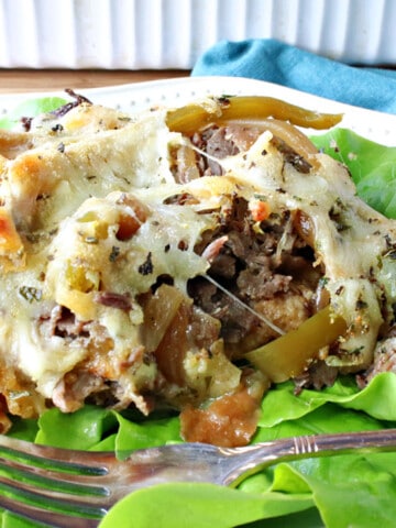 A serving of Savory Italian Beef Bread Pudding on a bed of lettuce with a fork.