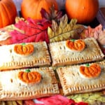 Four cute Pumpkin Hand Pies surrounded by autumn leaves.