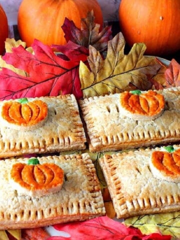 Four cute Pumpkin Hand Pies surrounded by autumn leaves.