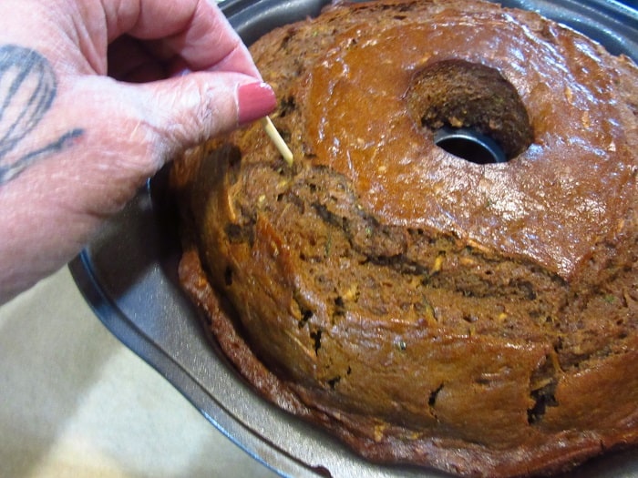 A toothpick being inserted into a Bundt cake.