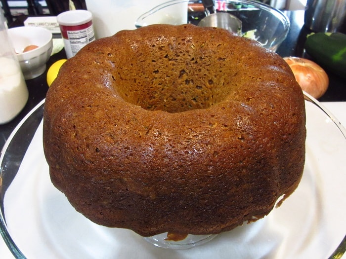 A baked Gingerbread Bundt Cake with Zucchini on a glass cake stand.