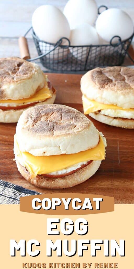 A vertical closeup of Copycat Egg McMuffin Sandwiches on a wooden board with a small basket of eggs in the background.