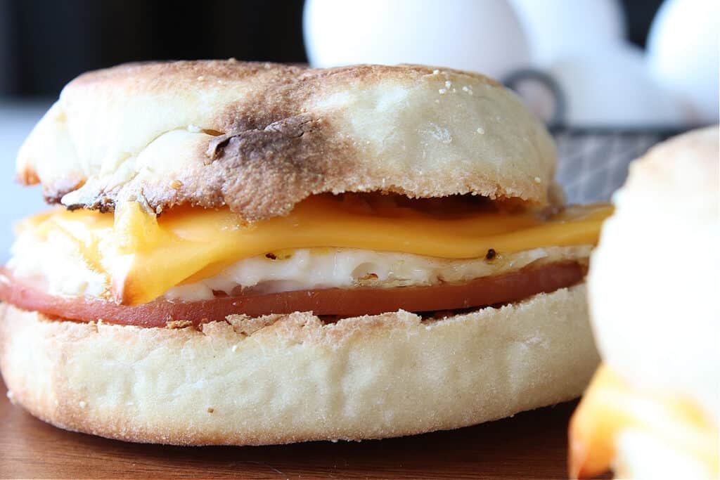 An offset horizontal closeup photo of a Copycat Egg McMuffin with American cheese, Canadian Bacon, and an English Muffin.