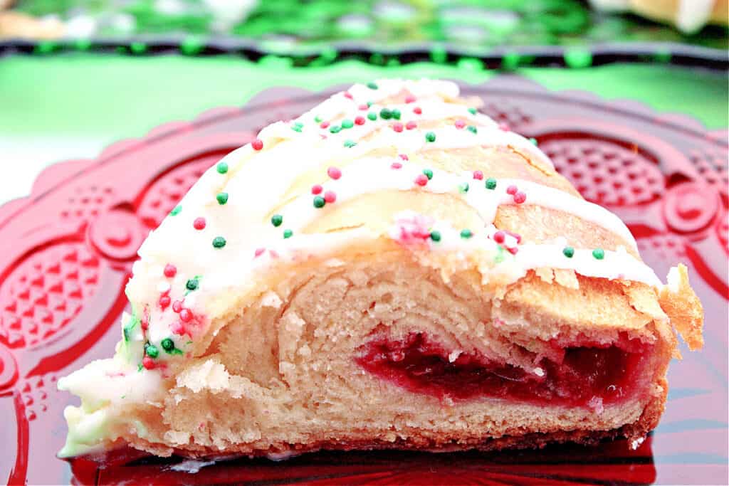 A slice of a Cranberry Kringle on a red glass plate with cranberry jelly and white chocolate icing.