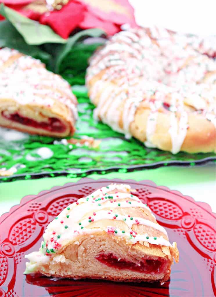 A slice of a Cranberry Kringle on a red glass plate in the foreground along with some Kringle pastries in the background.