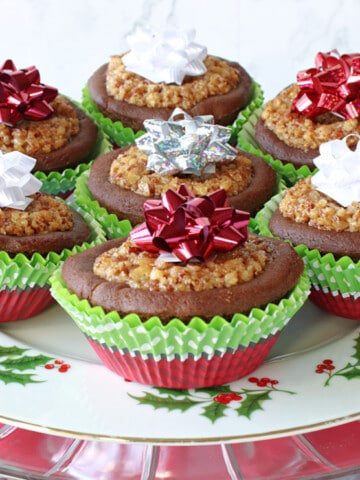 A festive plate filled with Gingerbread Pecan Pie Tarts with holiday bows on top.