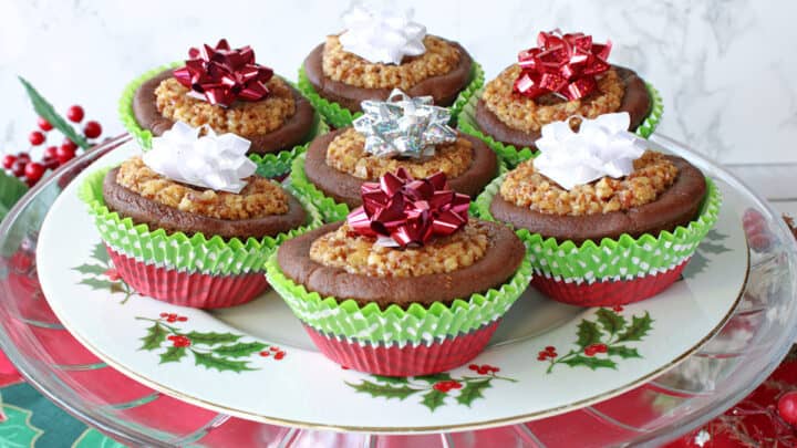 A festive plate filled with Gingerbread Pecan Pie Tarts with holiday bows on top.