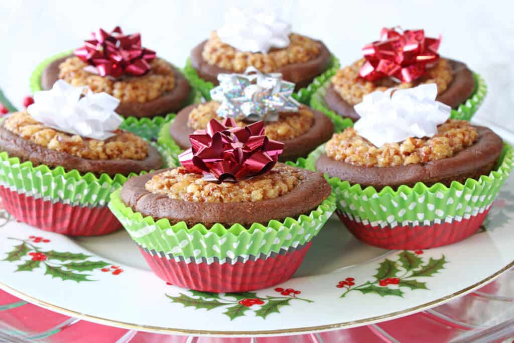 A festive holiday plate filled with Gingerbread Pecan Pie Tarts in festive wrappers along with holiday bows on top.