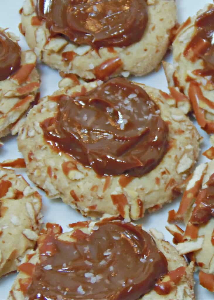 A vertical overhead closeup of Caramel Pretzel Thumbprint Cookies with a sprinkling of finishing salt.