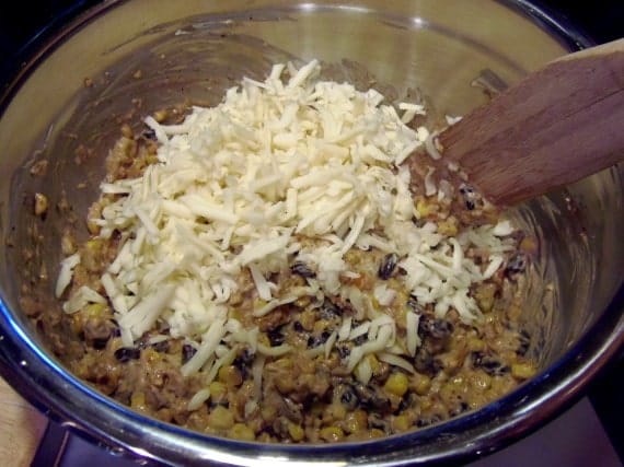 Cheese being mixed into a corn and bean dip.