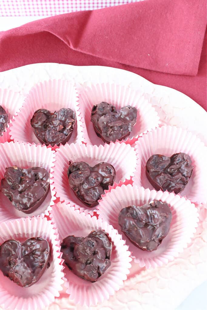 A vertical overhead closeup of Chocolate Covered Dried Cherries in red cupcake liner cups.