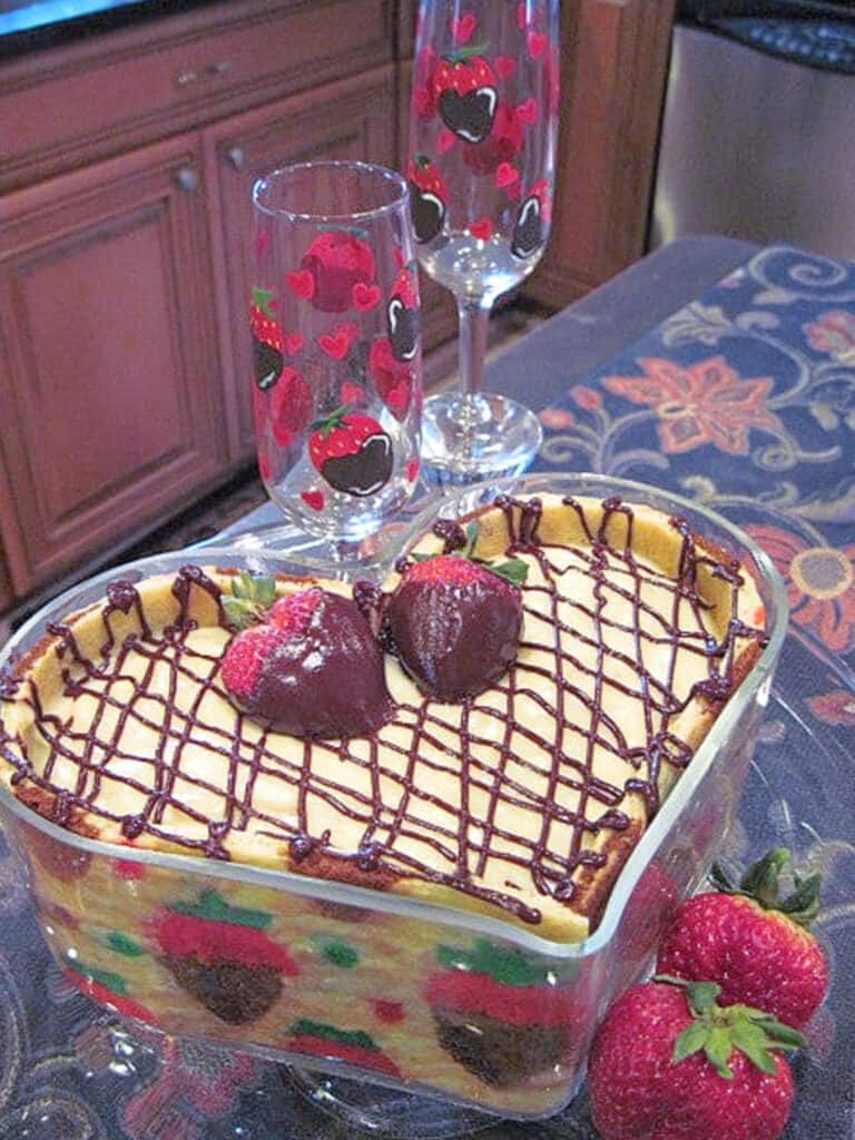 A pretty Chocolate-Covered Strawberry Joconde Entremet in a glass heart bowl along with fresh strawberries as garnish.