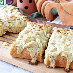 Slices of cheesy Chicken Alfredo Garlic Bread Pizza on a wooden cutting board.