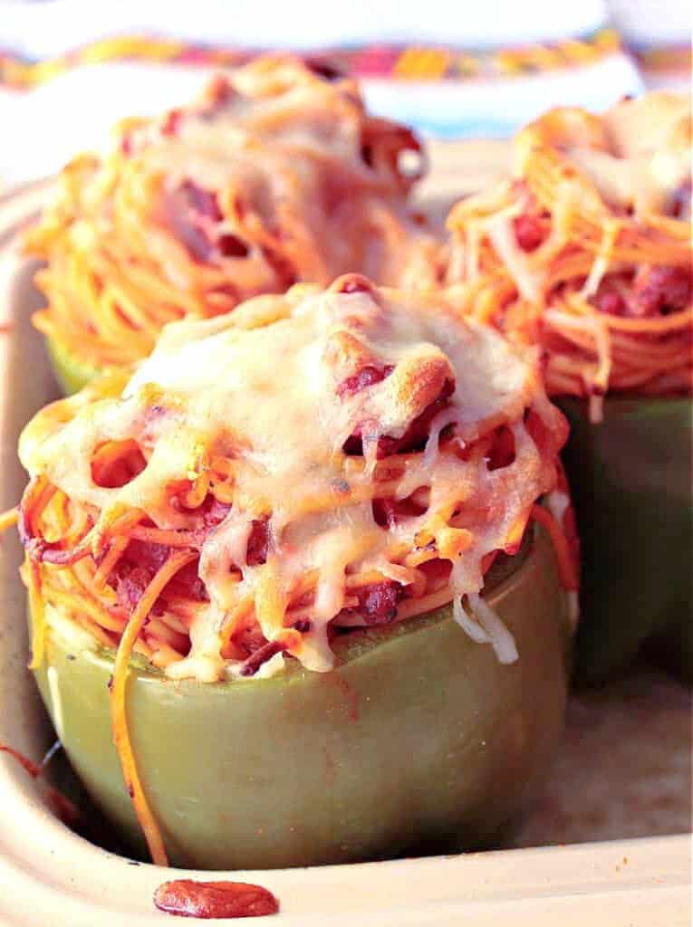 A vertical closeup of a Spaghetti Stuffed Bell Pepper topped with melted cheese.