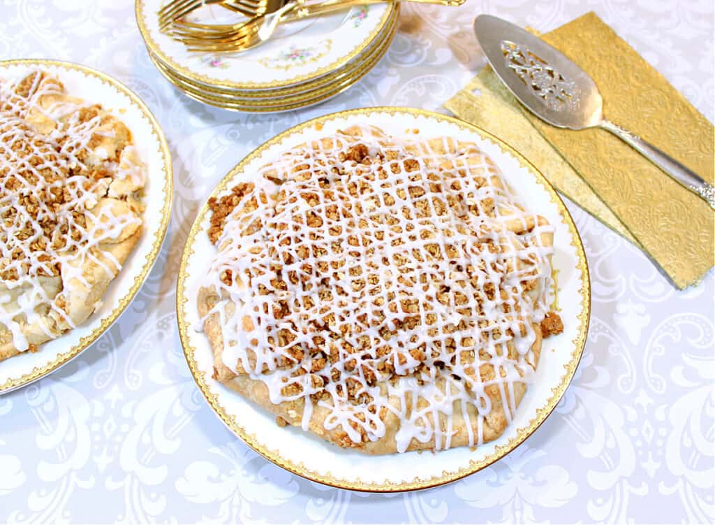 An overhead photo of two Apple Crumble Crostatas on gold tipped china plates with gold napkins on the side.