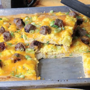 A baking sheet with a Scrambled Egg Breakfast Pizza with a slice taken out.