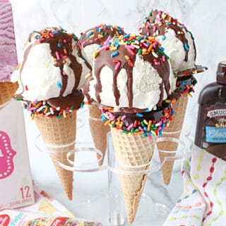 Four Ice Cream Cone Cake Pops in a holder with sugar cones and sprinkles.