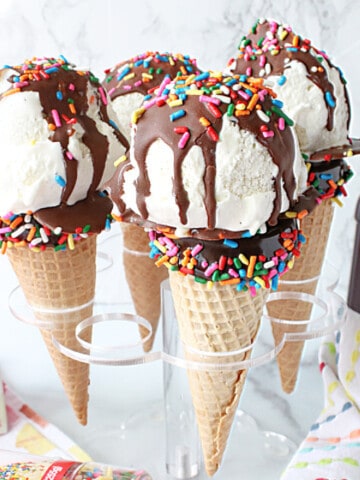 Cake Pop Ice Cream Cones with chocolate sauce and sprinkles in a holder.