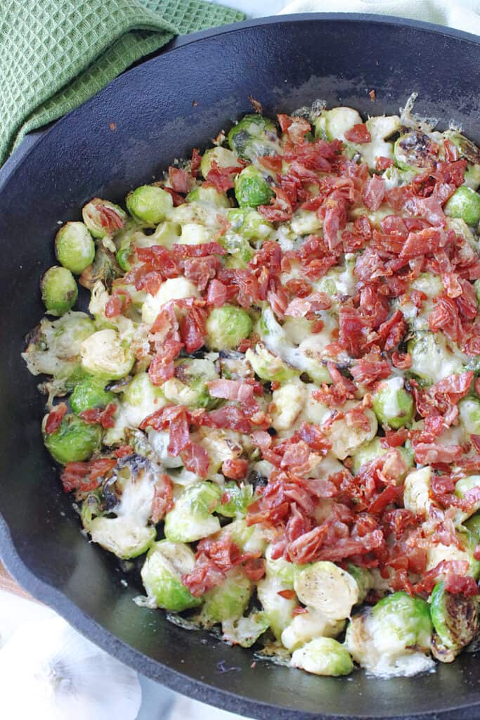An overhead vertical closeup photo of a cast iron skillet filled with Sautéed Brussels Sprouts and Crispy Prosciutto.