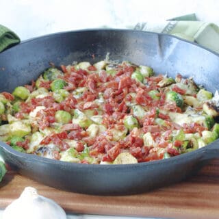 A cast iron skillet filled with Sautéed Brussels Sprouts with Crispy Prosciutto and some green napkins on the side.