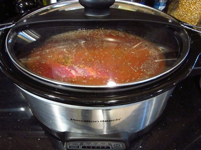 A covered slow cooker with a corned beef inside.