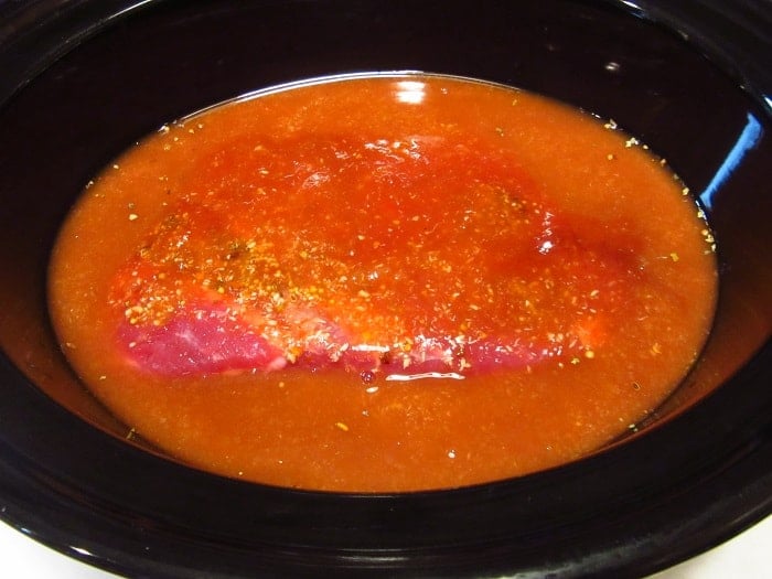A pickling liquid and corned beef in a slow cooker.