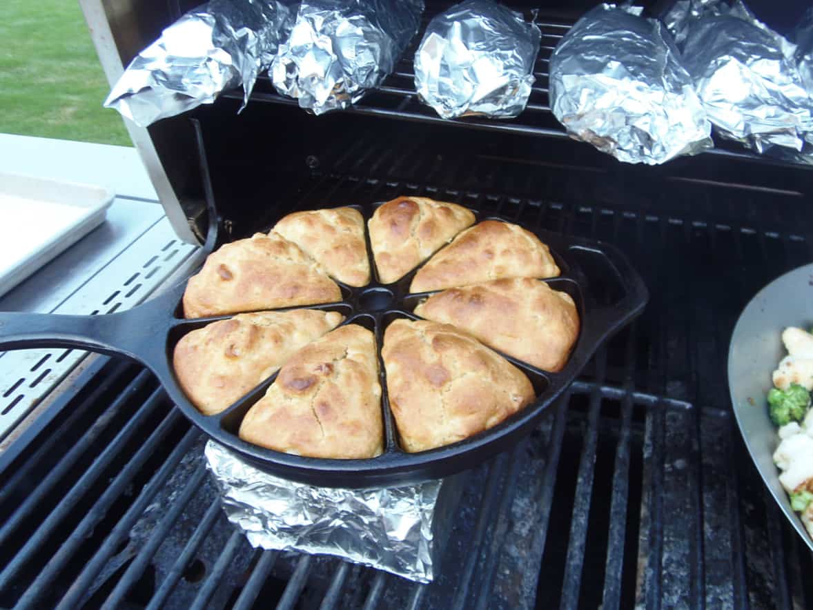 A divided cast iron skillet on the grill filled with golden brown Cast Iron Skillet Cornbread.