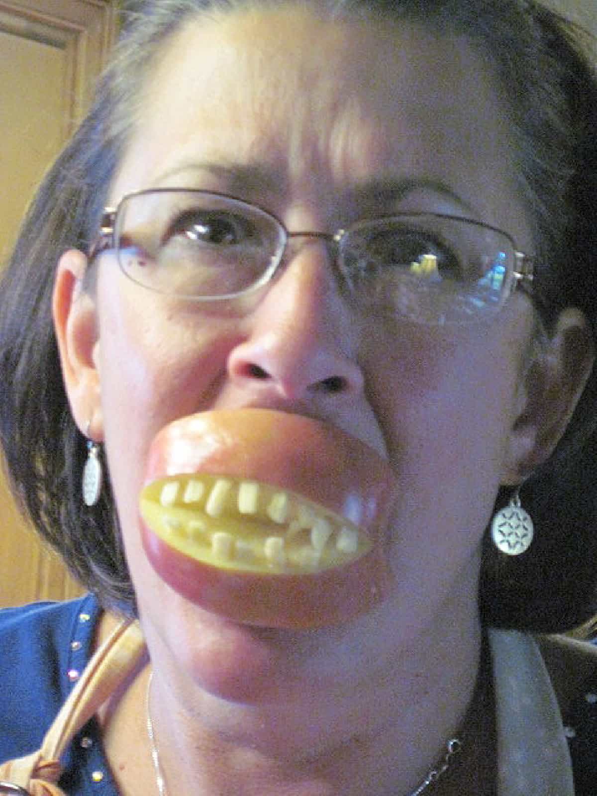A funny picture of a woman wearing Ghoulish Teeth Apple Snacks with almond pieces.