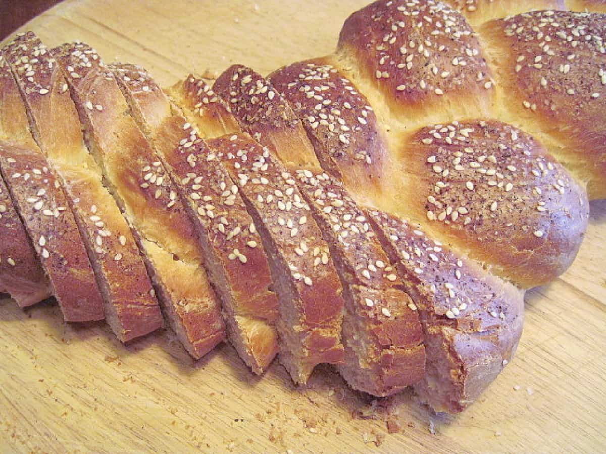 A sliced loaf of braided James Beard County Fair Bread with sesame seeds on top.