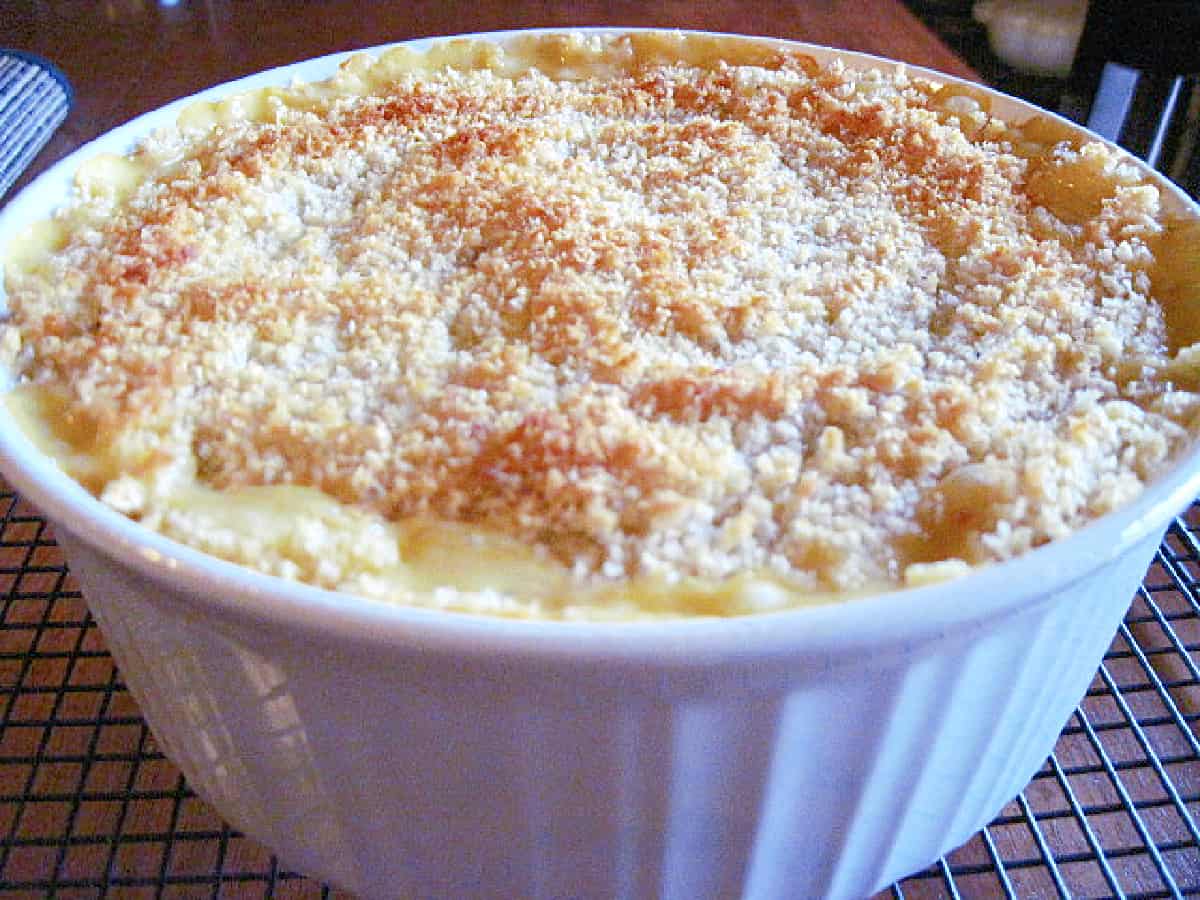 A round white casserole dish filled with Sweet and Cheesy Onion Casserole with a crunchy topping.