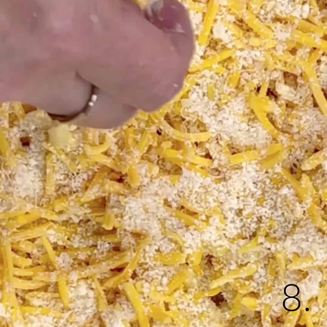 Additional cheeses being sprinkled over macaroni and cheese.