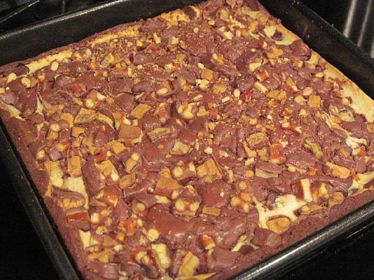 A full baking pan with baked Cream Cheese Brownies and take-5 candy pieces on top.