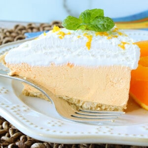 A pretty slice of Cream Cheese Kool-Aid Pie on a white plate with a sprig of mint and a fork on the plate.