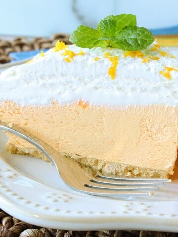 A pretty slice of Cream Cheese Kool-Aid Pie on a white plate with a sprig of mint and a fork on the plate.