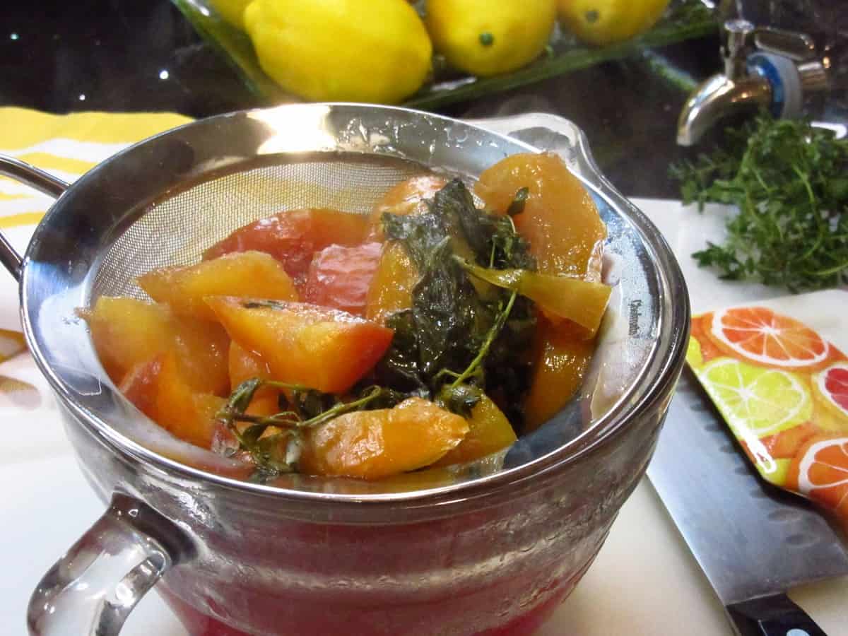 A strainer with chopped peaches and basil inside.