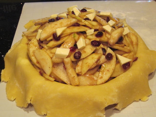 An Apple Pear Pie with Craisins in a pie plate with the bottom crust and waiting for the top crust.
