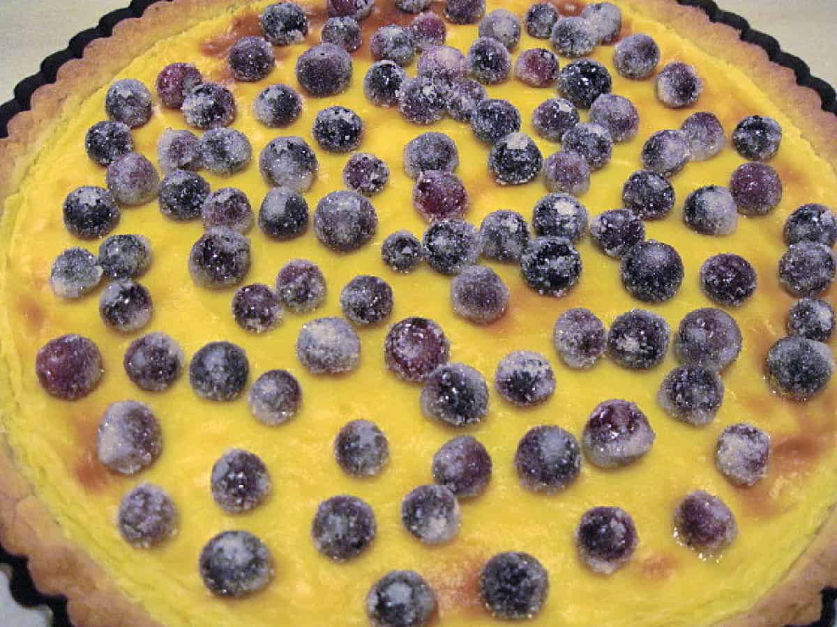 A closeup image of a Crostata with Pastry Cream and topped with sugared blueberries.