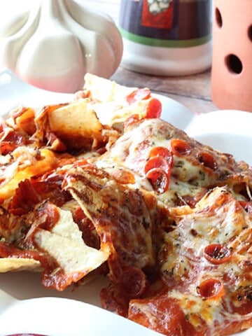 A serving of Pepperoni Pizza Nachos on a white plate with melted cheese and sauce.