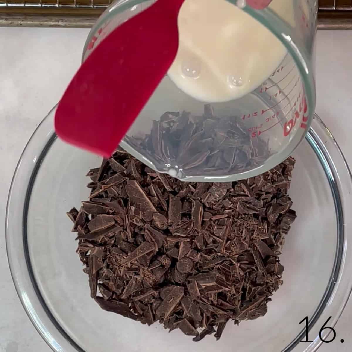 Chopped semi-sweet chocolate in a bowl with hot cream being poured into it.